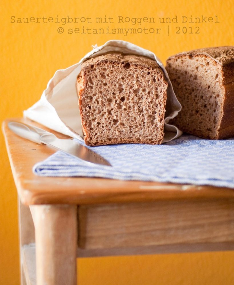 A loaf of sliced Sourdough Rye and Spelt Bread in front of a yellow background.