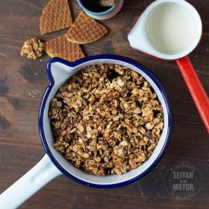 Granola in einem Topf, daneben Stroopwaffeln und Sojamilch.