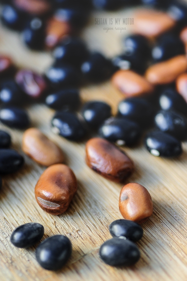 Fava beans and black beans on a wooden surface.