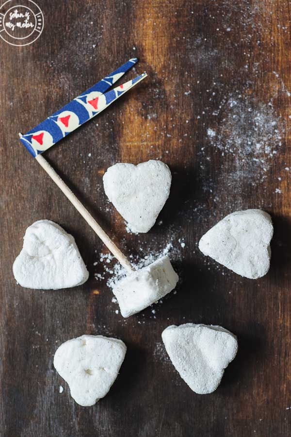 6 heart shaped vegan marshmallows on a wooden board.