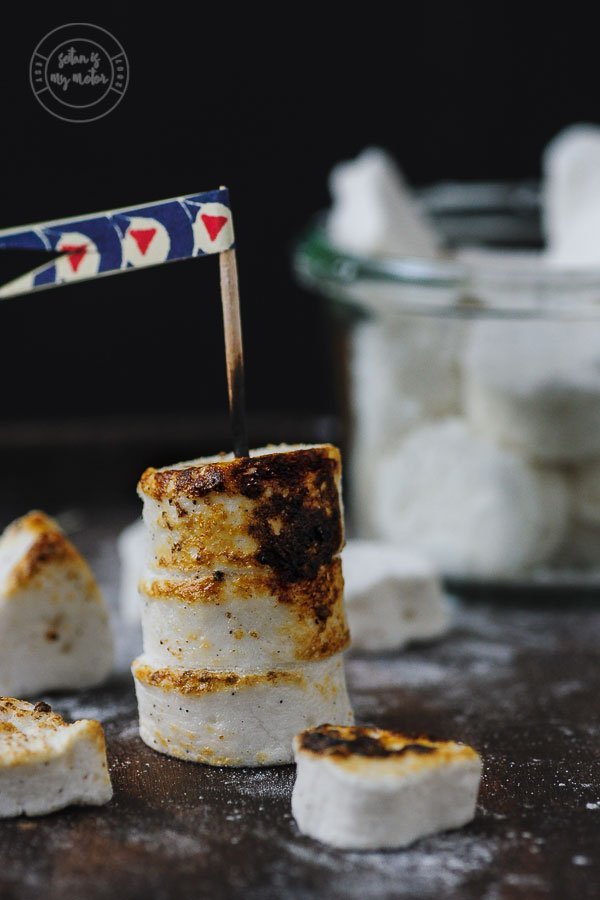 Drei aufgespießte, getoastete vegane Marshmallows.