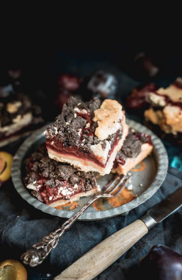 Three square slices of plum cake of a metal plate.