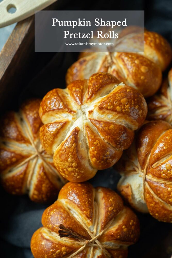 A couple of pumpkin shaped pretzel rolls in a wooden box.