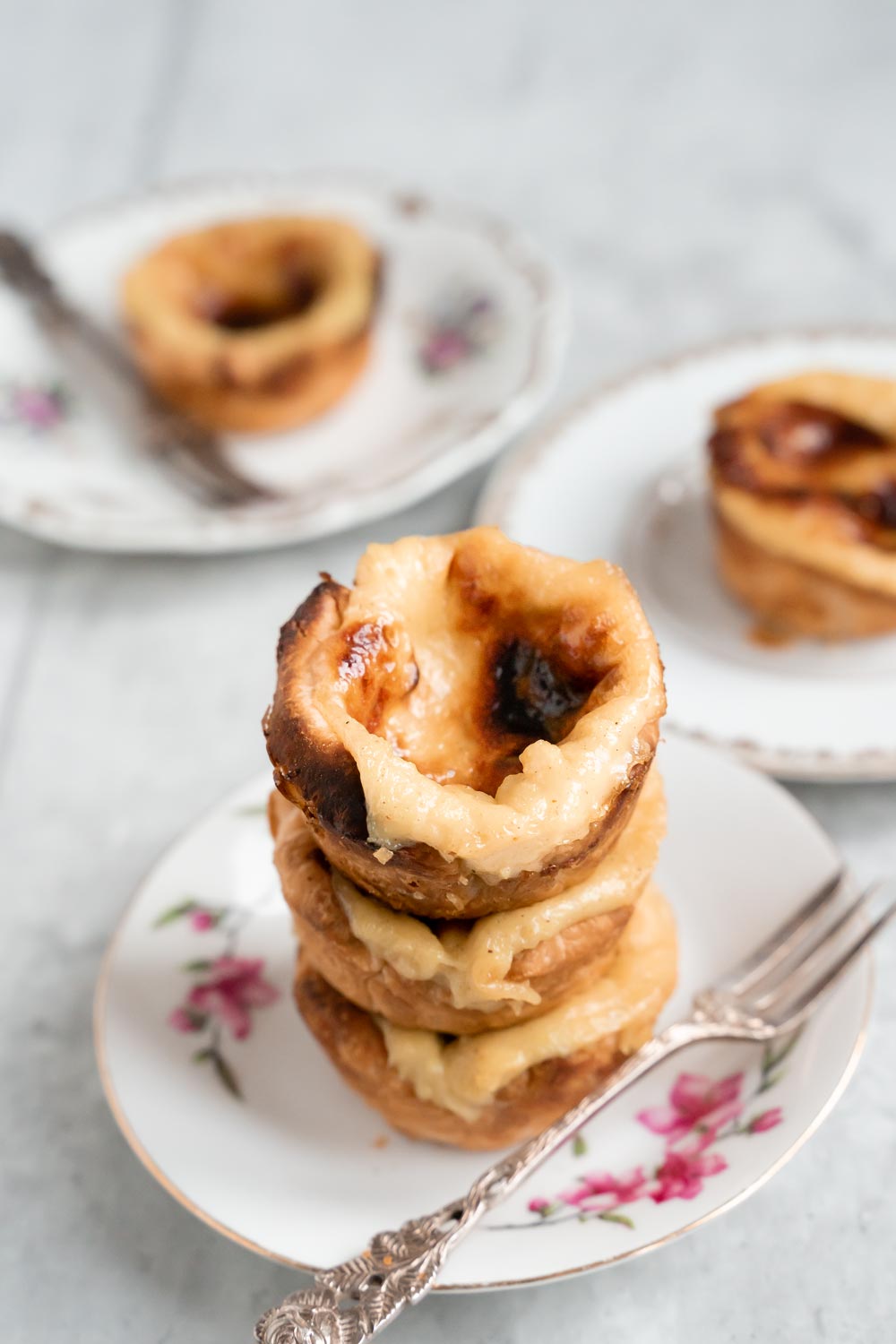 Threee vegan pasteis de natat stacked on top of each other.