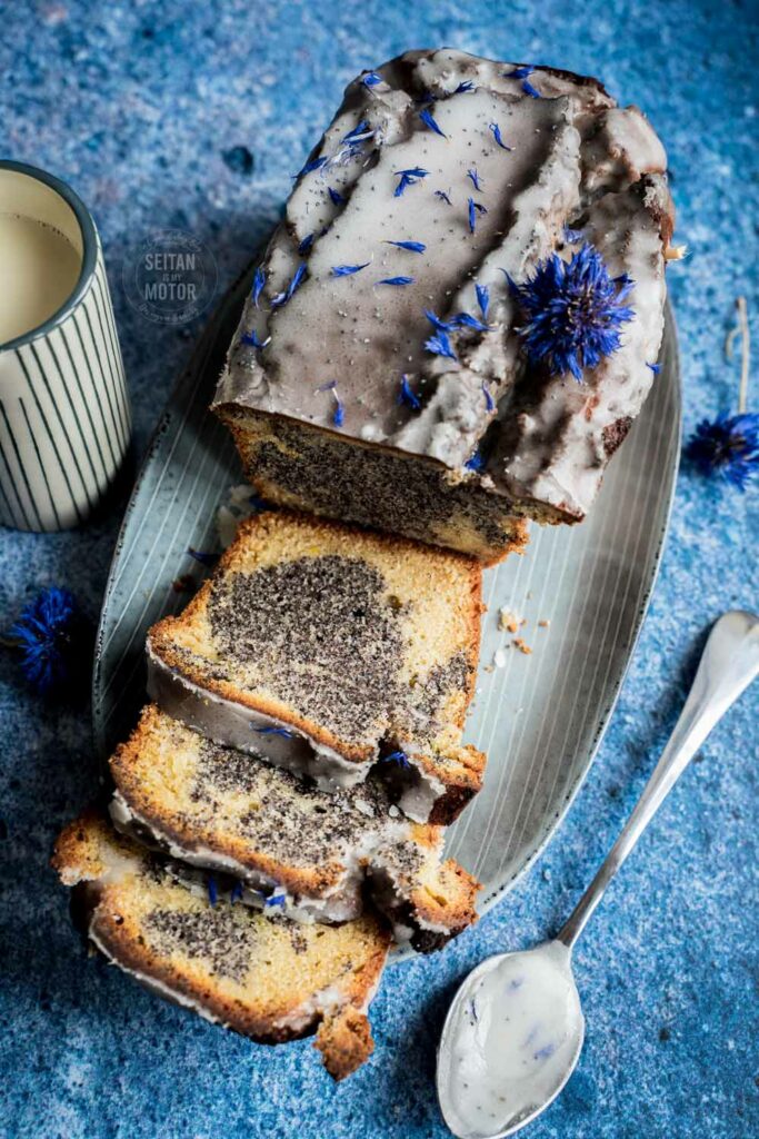 A poppy seed marble cake in a loaf shape on a large plate. The cake is sliced.